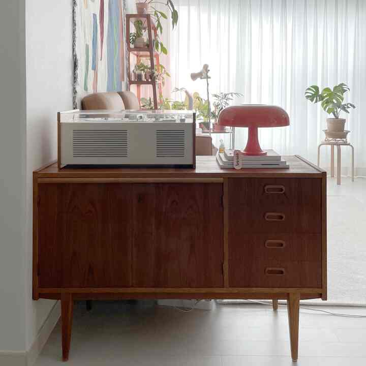 ナチュラルな色調のリビング、ヴィンテージのキャビネットにLPターンテーブルと赤いスタンドランプが配置された雰囲気のあるインテリア