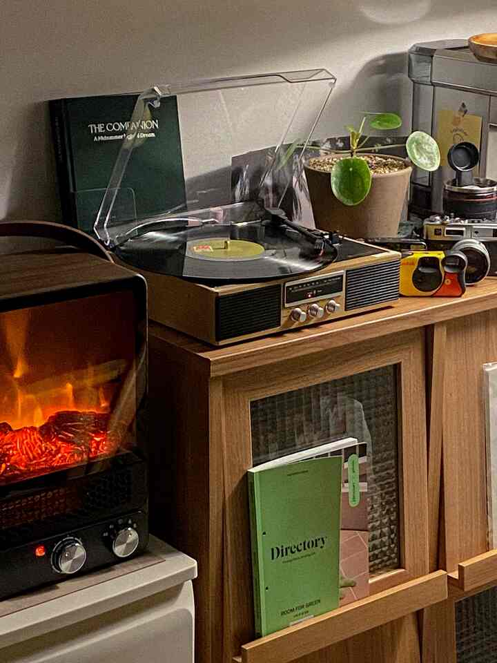 ブラウン調のヴィンテージリビング、ターンテーブルとフィルムカメラ、暖炉が温かみのある雰囲気を作る空間