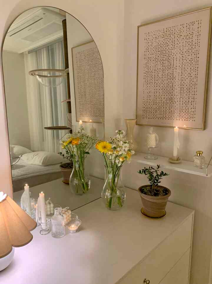 白とナチュラルの色調の寝室、花瓶とキャンドルが配置された雰囲気のあるインテリア