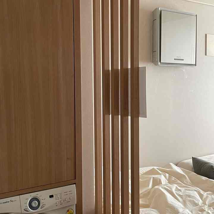 ナチュラルな木目調と白を基調とした寝室、ストライプの間仕切りが配置された雰囲気のある空間