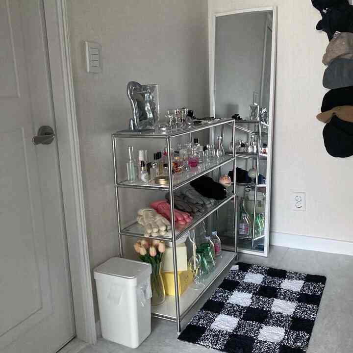 グレーとホワイトのモノトーンの玄関スペース、金属製の棚と全身鏡、白黒のチェック柄ラグが配置された機能的で整ったインテリア