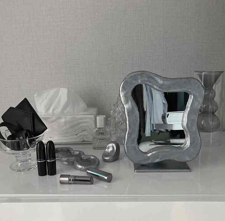 ナチュラルカラーの化粧台空間、独特な鏡とリップスティックなどの化粧品がミニマルに美しく配置された雰囲気のあるインテリア