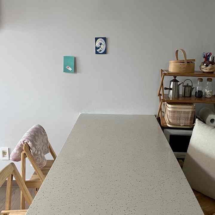 ベージュと木目調のキッチン、大きなダイニングテーブルとキッチン用品が並ぶ木製シェルフが配置された雰囲気のある空間