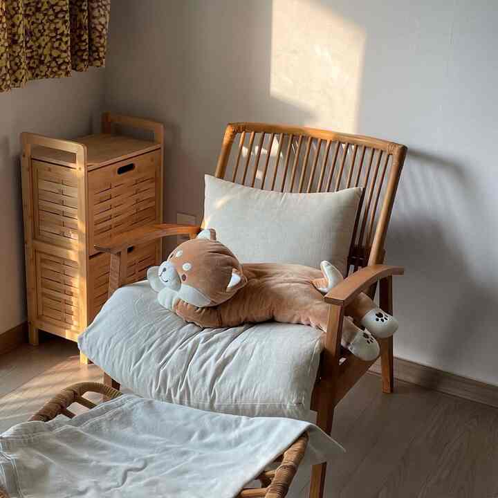 ナチュラルなベージュ調の小さな空間、ラタンのアームチェアとスツールが配置され、落ち着いた雰囲気のインテリア