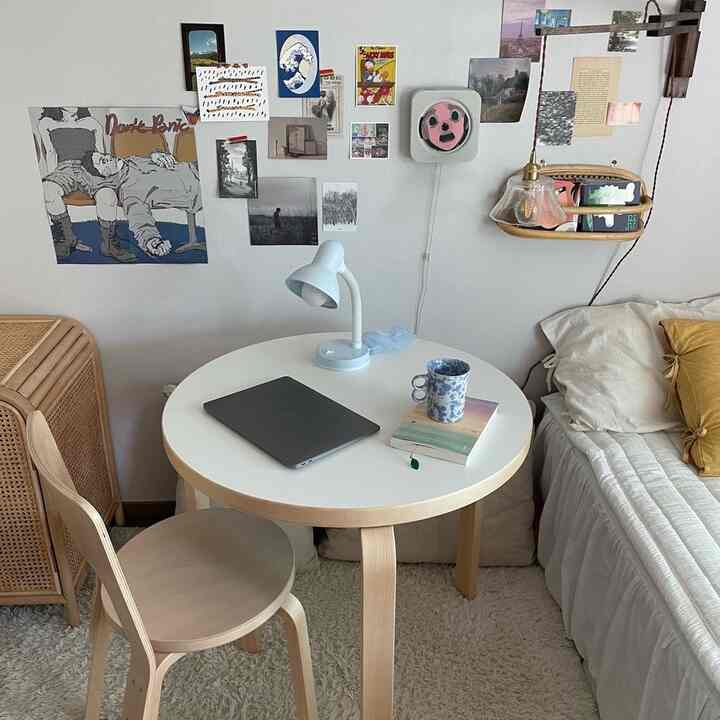 ナチュラルモダン調の寝室、丸テーブルとラタン収納キャビネット、壁に多彩なアートが配された雰囲気のあるインテリア