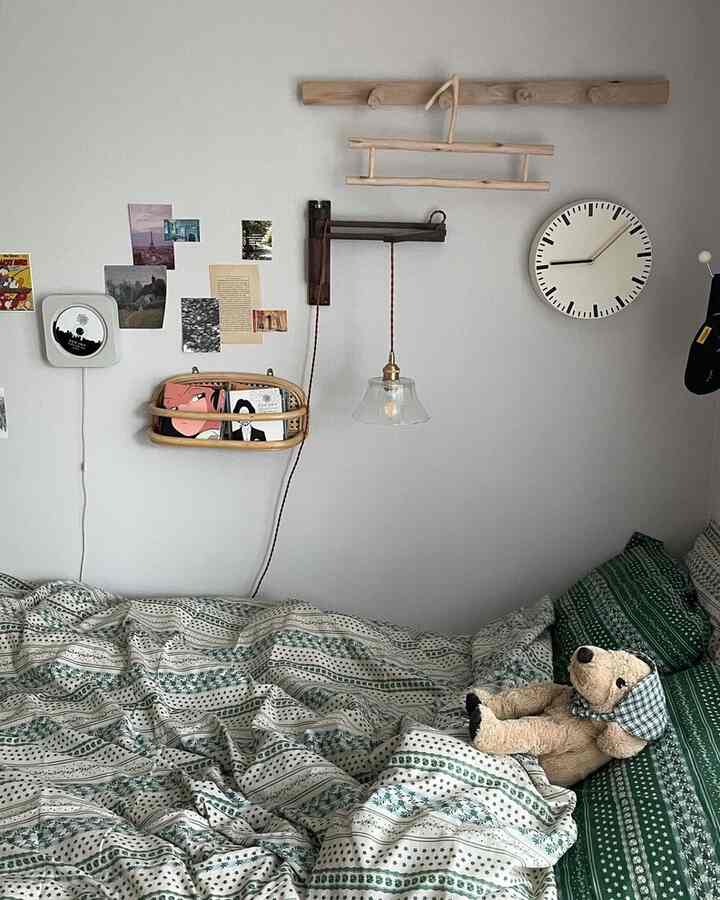 ナチュラルカラーと木目調の6畳寝室、ベッドにぬいぐるみ、壁付け照明と時計が配置された雰囲気のあるインテリア