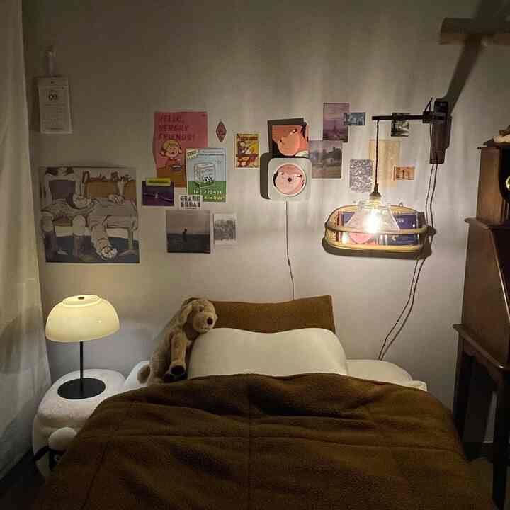 ブラウンとホワイトの落ち着いた寝室、ベッドの上に犬のぬいぐるみと壁付け照明が配置された雰囲気のあるインテリア