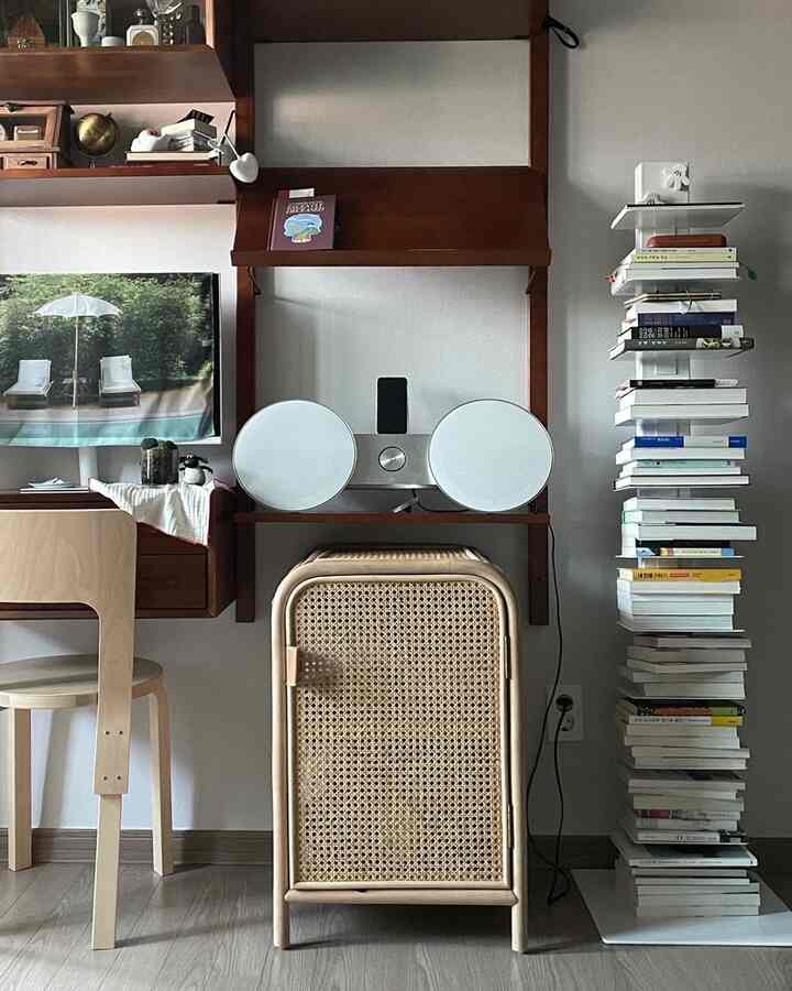 ナチュラルな色調の小さな部屋、ラタン収納キャビネットと木製の壁棚、本棚が配置された落ち着いたワークスペース