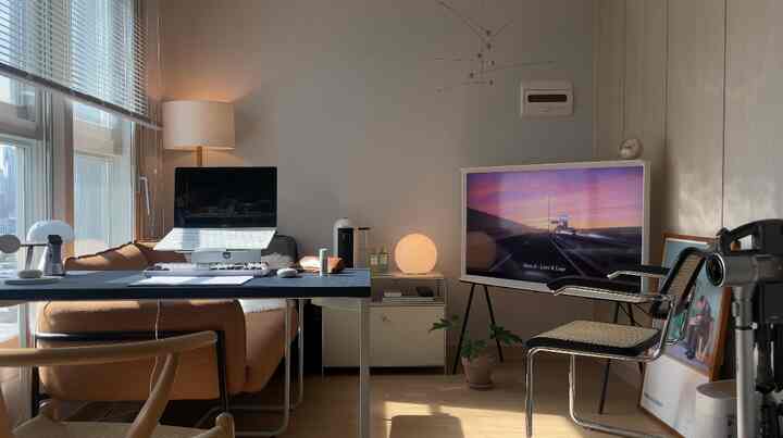 白とベージュの落ち着いた色調のワンルームリビング兼ホームオフィス、ソファやデスク、テレビが配置された雰囲気のある空間