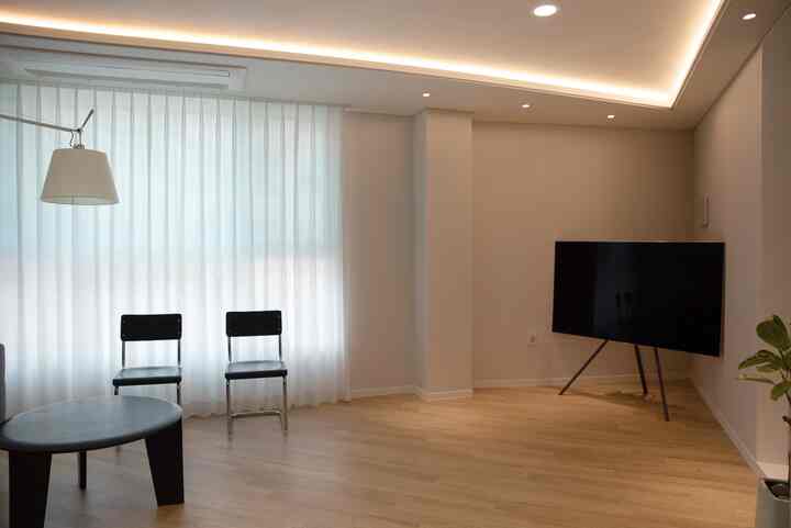 白と木目調が調和するリビング、テレビ台と椅子が配置されたシンプルでモダンなインテリア