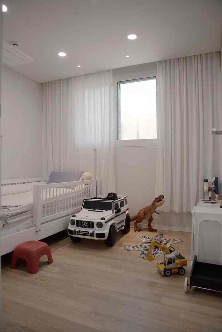 白とナチュラルカラーの子供部屋、ベビーベッドとおもちゃが配置された雰囲気のある空間