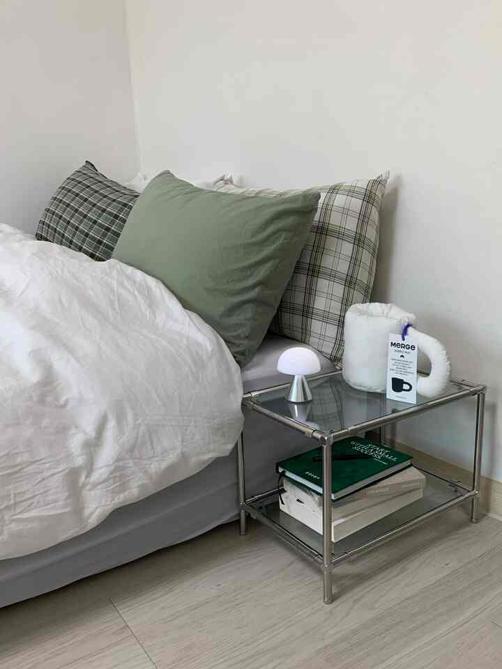 白とナチュラルカラーの調和した寝室、清潔感のある寝具と金属製のナイトテーブルが配置されたモダンな空間