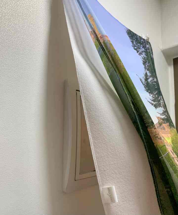 白い壁と半透明のシフォンポスターが掛かった玄関、清潔感と自然な雰囲気のあるインテリア