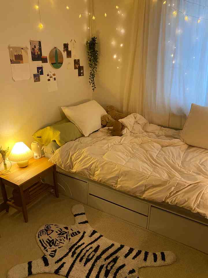 温かみのあるベージュ色調の寝室、居心地の良いベッドと木製ナイトテーブル、壁に装飾照明が配置された雰囲気のあるインテリア