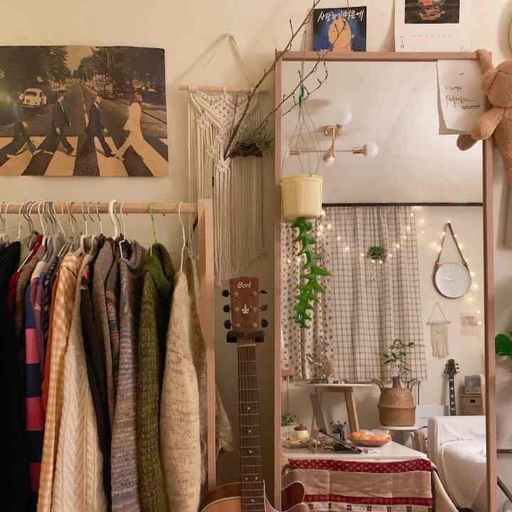 ナチュラルな色調のワンルーム、壁にかけられた大型鏡と洋服ラックが配置された雰囲気のあるインテリア