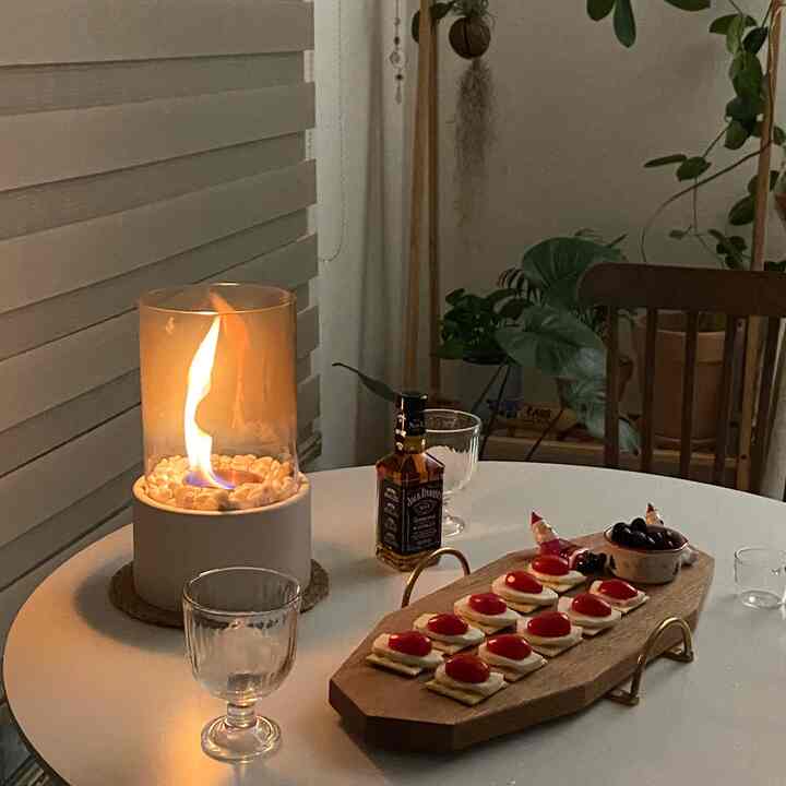 ホワイトとブラウンのトーンのダイニング、丸テーブルにホームバーアイテムとエタノールランプが配された雰囲気のある空間