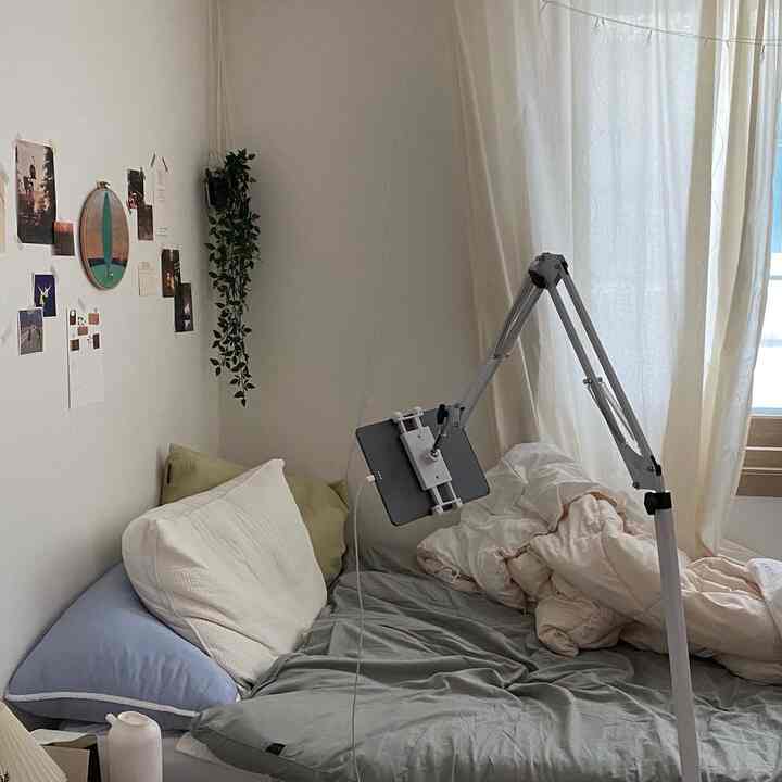 ナチュラルなベージュとホワイトのトーンの寝室、ベッドとiPadスタンドが配置された落ち着いた空間