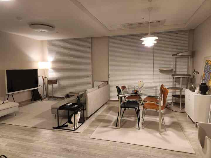 明るいホワイトとベージュのトーンのリビング、ソファとダイニングテーブル、キャットタワーが配置された落ち着いたモダンな空間