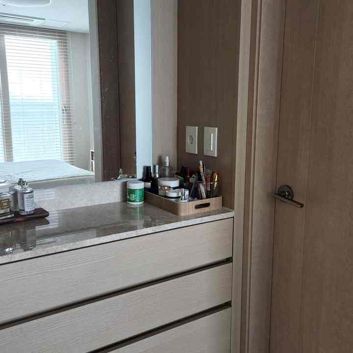 木目調のナチュラルな寝室、化粧台として使われるチェストとその上に置かれたウッドトレイと化粧品が配置された落ち着いた空間