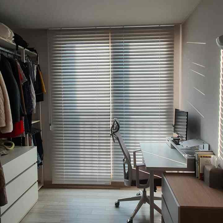 白と木目調でまとまったウォークインクローゼットとホームオフィスの空間、机とオフィスチェアが配置された整ったインテリア