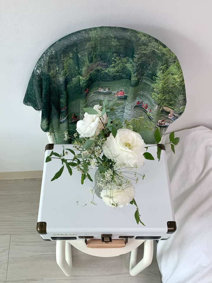 白を基調としたキッチンスペース、椅子に中央公園のシフォンポスターと透明な花瓶が配置され、清潔で自然な雰囲気のインテリア