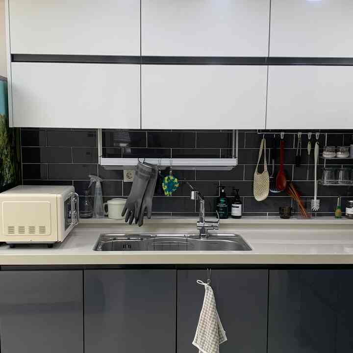 白と黒の色調のキッチン、シンクと電子レンジ、キッチンタオルが整然と配置されたモダンな空間