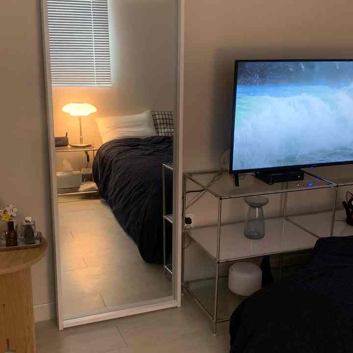 白と黒のトーンの寝室、大きな鏡とサイドテーブルが配置された清潔でモダンな空間