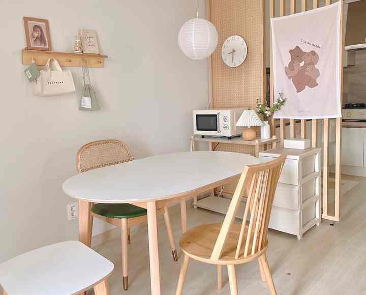 白と木目調の調和がある狭いリビング、ダイニングテーブルと椅子、壁棚が配置された清潔感のあるナチュラルモダンなインテリア