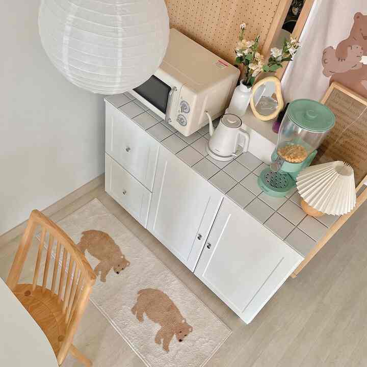 白と木目調のキッチンスペース、白いキャビネットと木製の椅子が配置された自然で温かみのあるインテリア