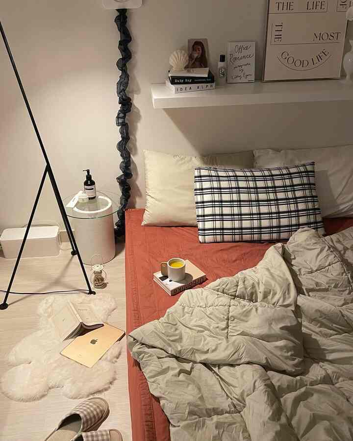 ナチュラルな色調の小さな寝室、赤みがかったベッドカバーとベージュの掛け布団が配置されたシンプルな空間