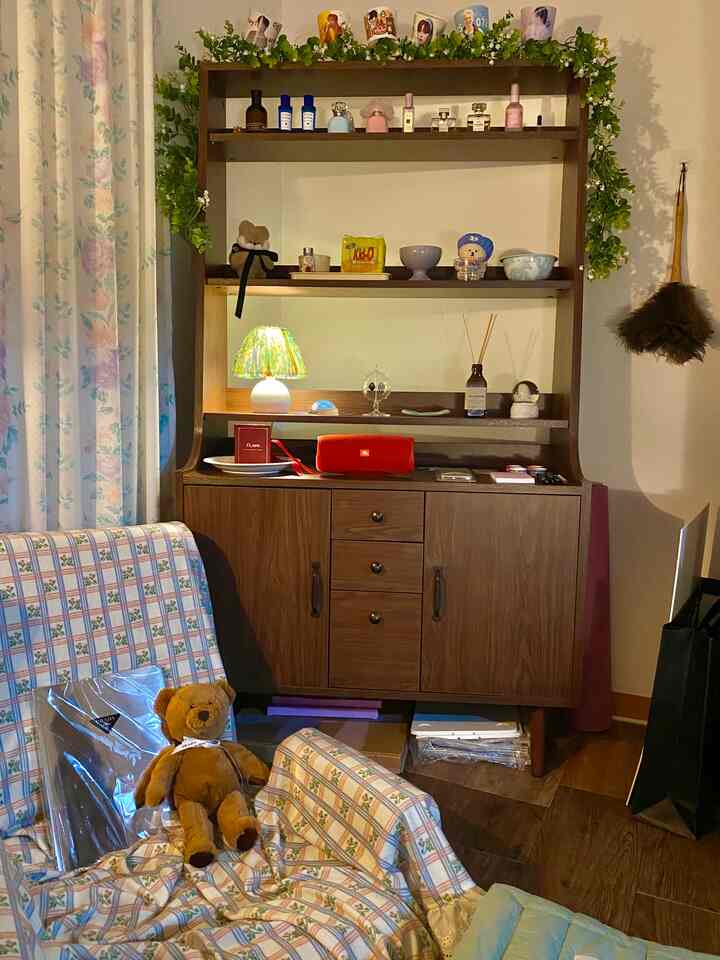 暖かいウッドトーンとブラウンのリビング、キャビネットとテーブルランプ、花柄のカーテンが配置された雰囲気のあるインテリア