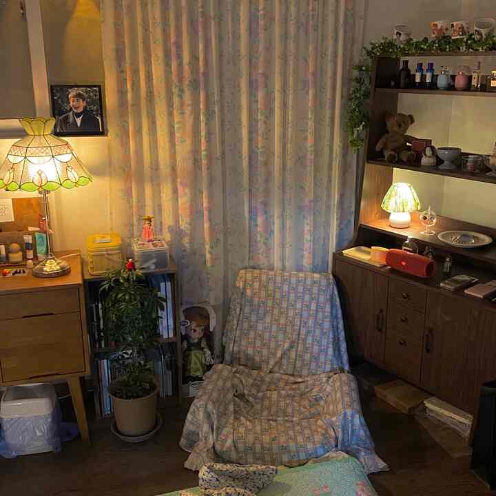 ラベンダーカラーのリビング、花柄カーテンと座椅子、木製収納棚とテーブルランプが温かみのある雰囲気を演出するインテリア