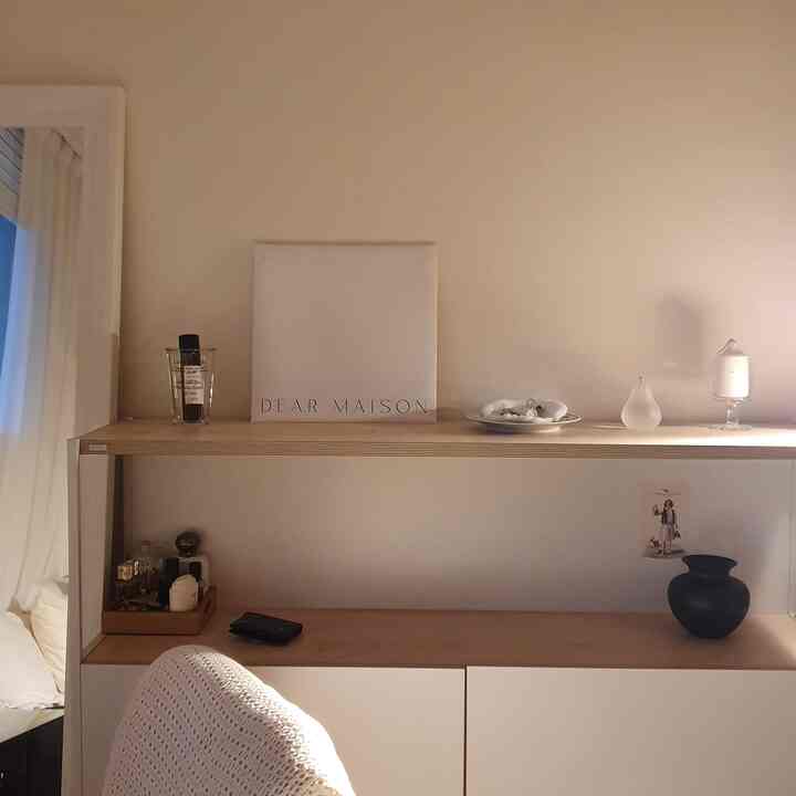 ベージュと白を基調とした玄関スペース、シンプルな収納とキャンドルや花瓶などのオブジェが配置されたミニマルで落ち着いた雰囲気のインテリア