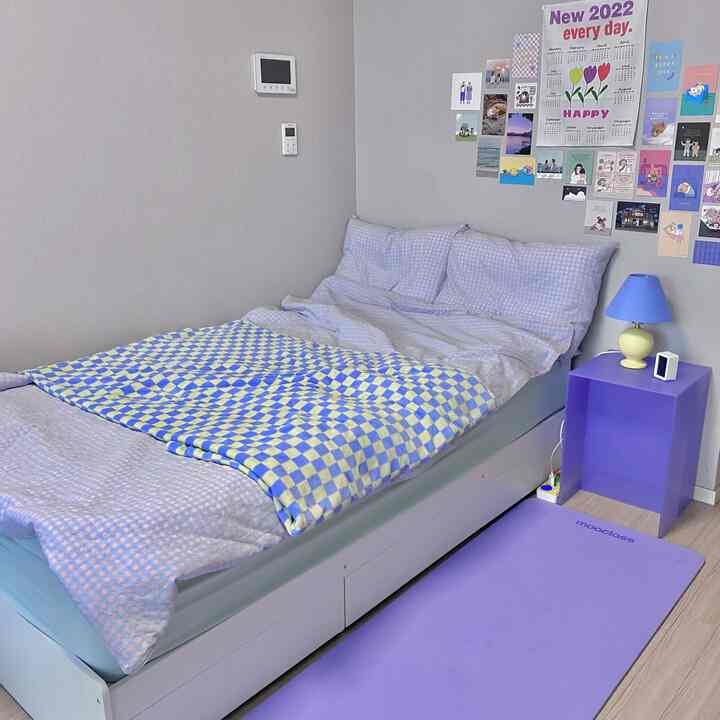 グレーの壁とライトブラウンの床の寝室、パープルのナイトテーブルとマットレス付きベッドが配置された雰囲気のある空間