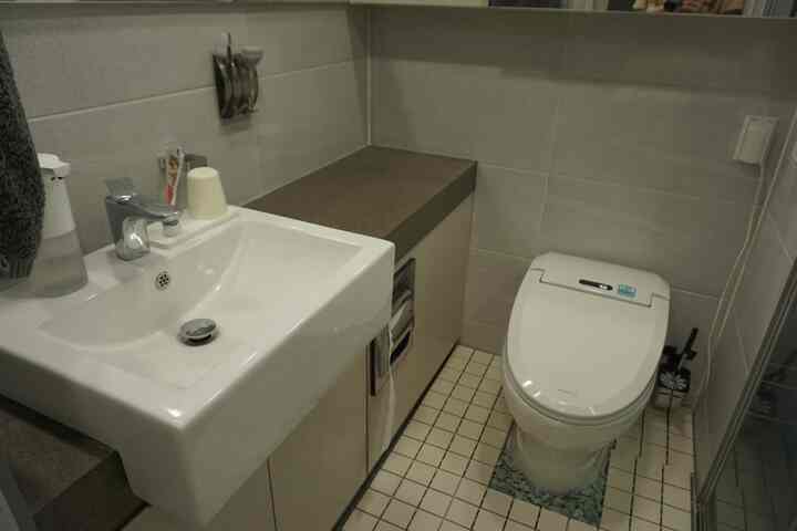 グレーと白の色調の狭いトイレ、清潔感ある洗面台と便器が配置されたコンパクトな空間