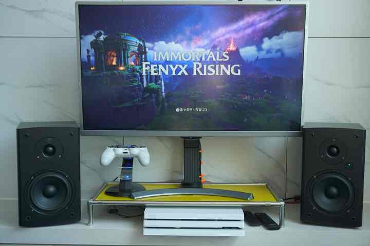 ホワイトとブラックのトーンのキッチン内ゲームルーム、大型モニターとプレイステーションコンソールが配置された印象的な空間