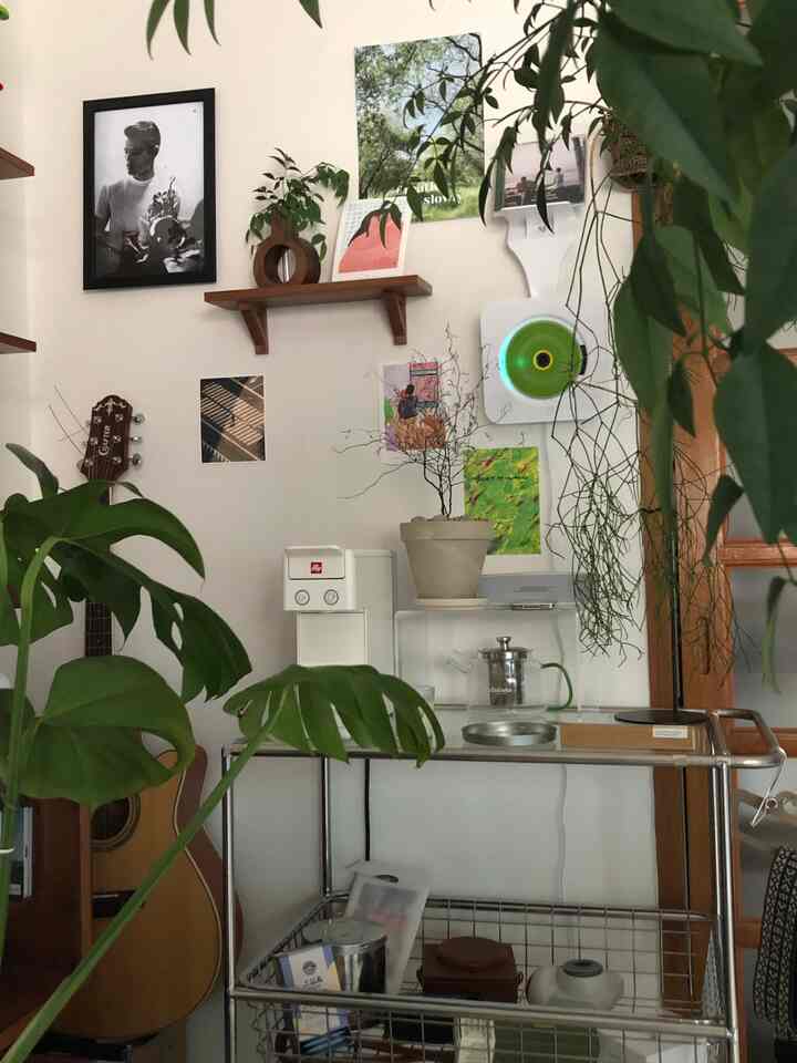 白とナチュラルトーンのリビング、コーヒーマシンやガラスの棚、植物が配置された心地よく開放的なインテリア