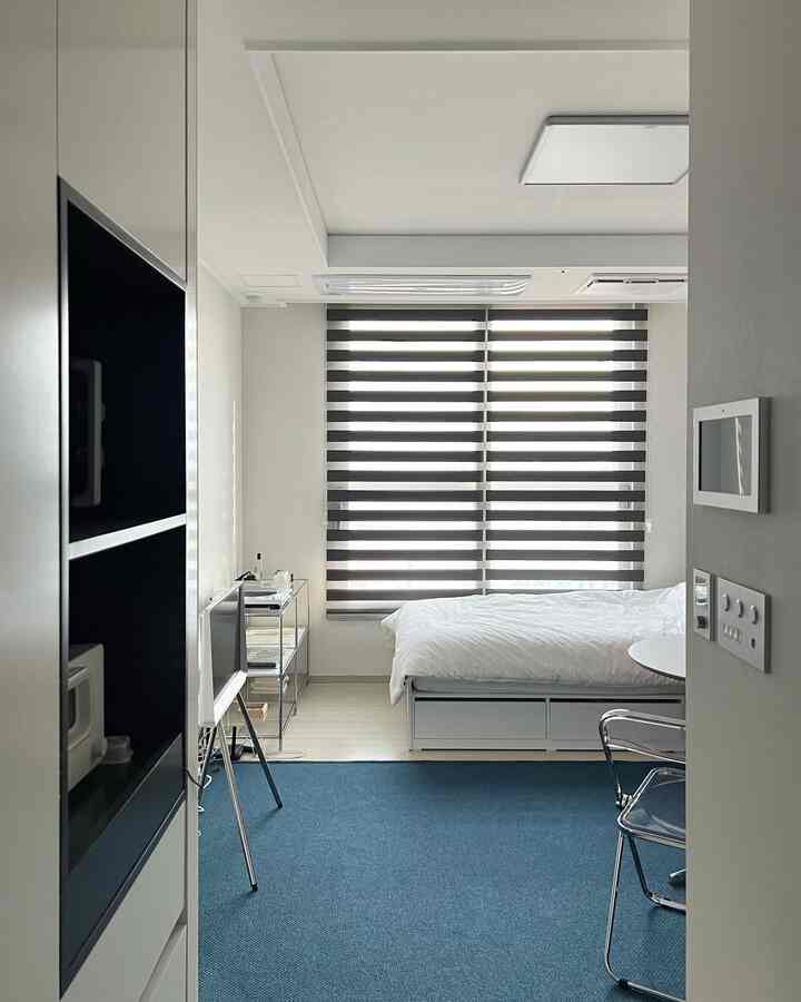 白と青の色調の寝室、収納ベッドとレイヤードブラインドが配置されたモダンで整ったインテリア