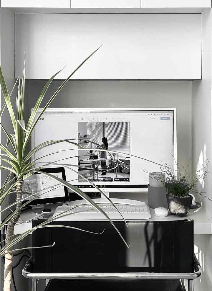 白と黒のミニマルなホームオフィス空間、モニターと植物が配置された清潔感と集中力を高めるワークスペース