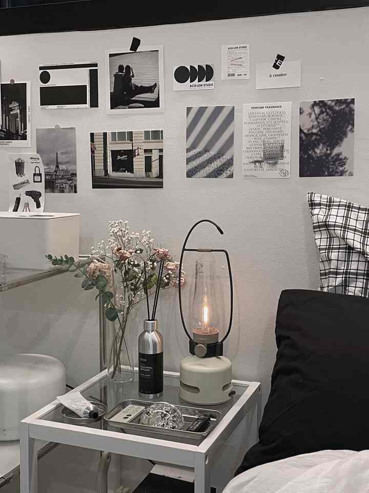 白黒のトーンが際立つ寝室の一角、サイドテーブルに配置されたムードライトと花瓶が調和するミニマルな空間
