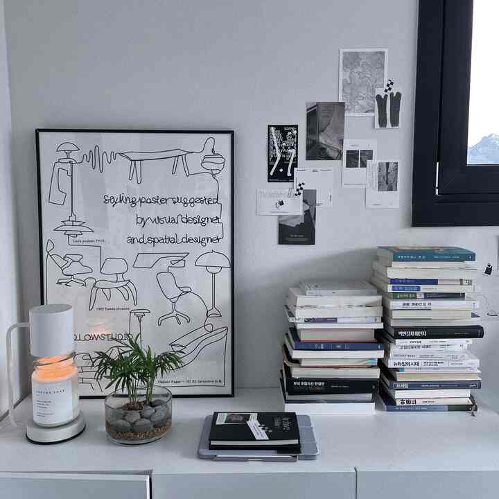 ホワイトトーンの空間に高さのある収納の上に本と額縁が配置されたミニマルな読書空間