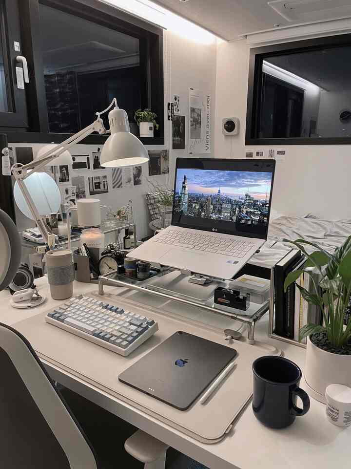 白と黒のトーンでまとめられたシンプルモダンなホームオフィス、デスクにノートパソコンとiPad、植物が配置された落ち着いた空間