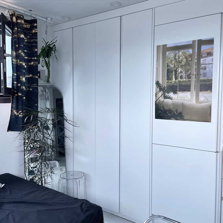 白色のビルトインクローゼットと全身鏡、アラリアの観葉植物が配置されたシンプルで清潔感あるインテリア