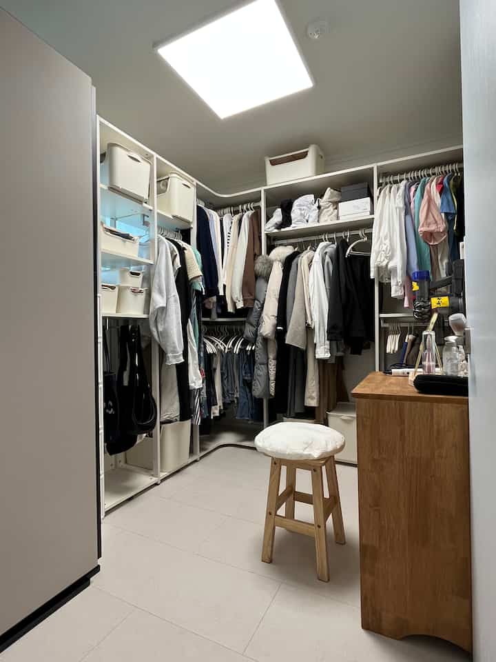 白と木目調の調和があるウォークインクローゼットで、整った収納棚とハンガーが印象的な空間