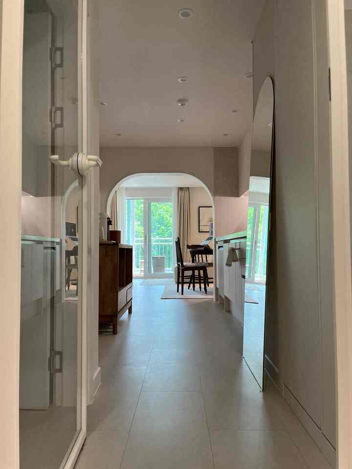 白と木目調の玄関から見えるアーチ型入口、キッチン、リビングが調和したナチュラルモダンのインテリア