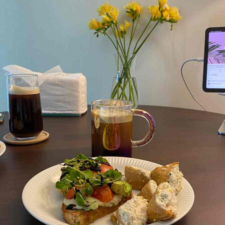 ナチュラルカラーのリビング兼ダイニングスペース、中央に大きなダークブラウンのダイニングテーブルとグラス、花瓶が配置された落ち着いたおうちカフェの雰囲気のあるインテリア