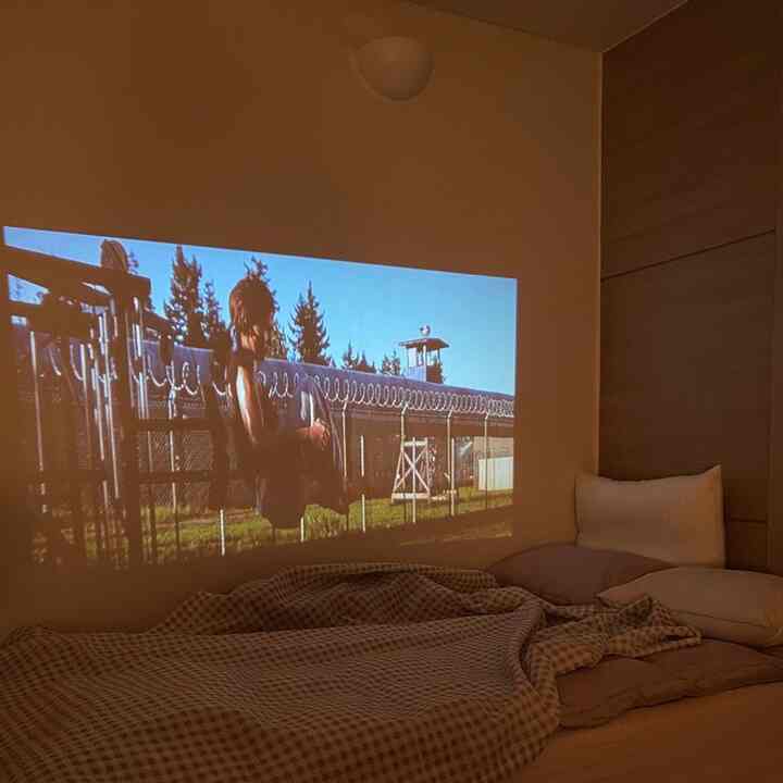 暖かいベージュとブラウンの色調の寝室、ソファベッドとプロジェクターが配置されたホームシネマスペース