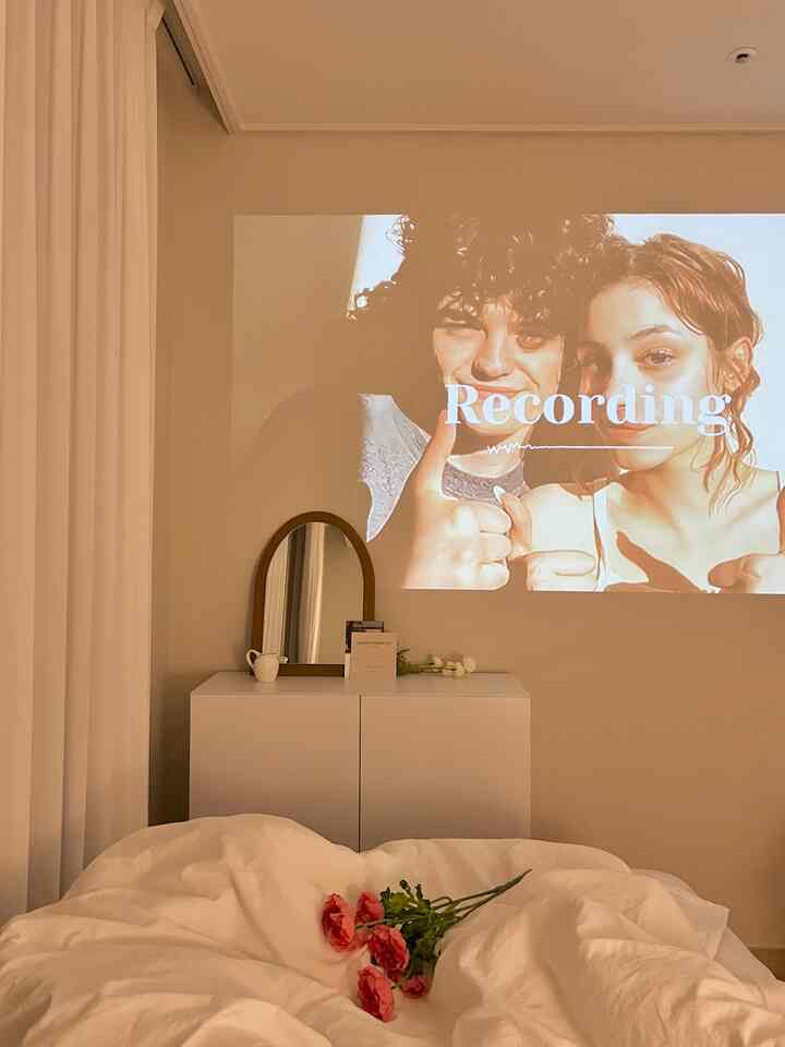 明るいアイボリー色の壁と白い収納家具が配置された寝室、アーチ型の鏡と白い掛け布団で落ち着いた雰囲気のインテリア