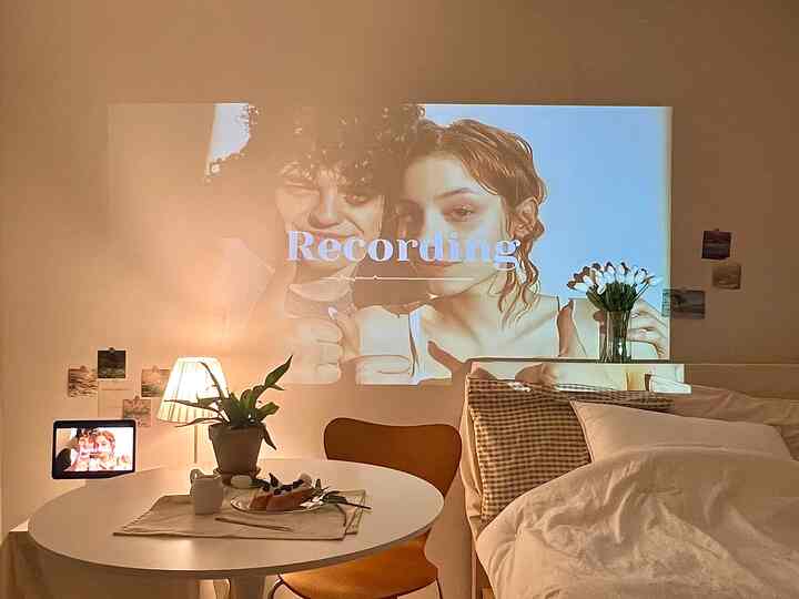 暖かいホワイトとブラウンの色調のワンルーム寝室、壁にホームシネマの映像が投影された雰囲気のある空間