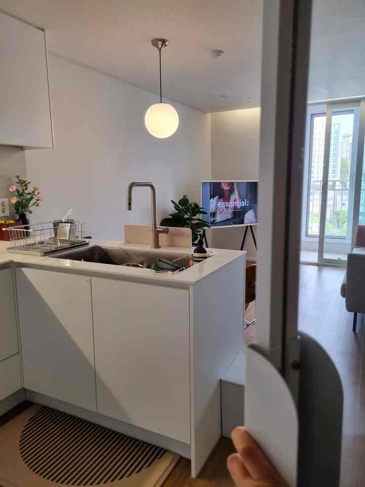 白を基調としたキッチンとリビングの一体空間、モダンでナチュラルな小物が配置された印象的なインテリア